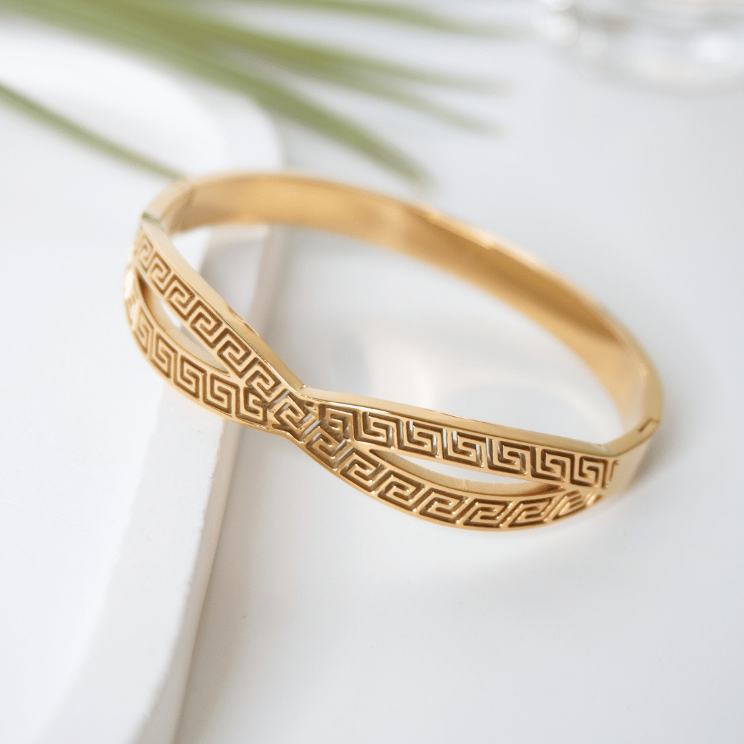 Gold bracelet with intricate pattern on a white surface